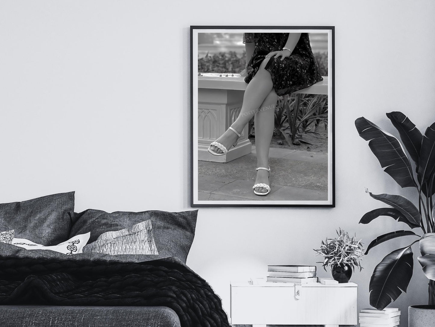 Framed black and white print of a person's legs in high heels on a wall above a bed.