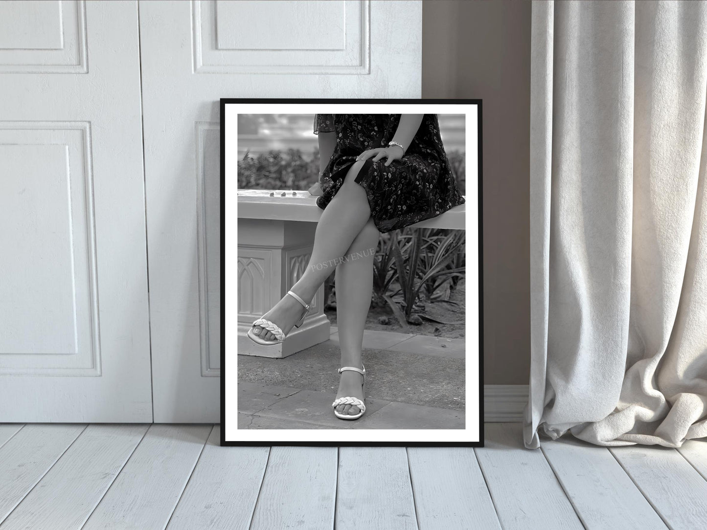 Framed black and white print of a person sitting on a bench with legs crossed.