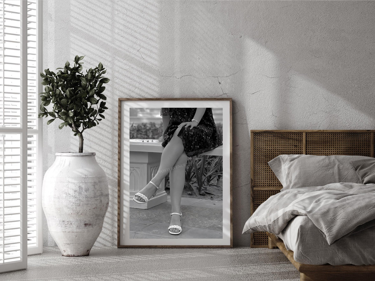 Framed black and white photo of a person in a bathroom on a wall in a bedroom.