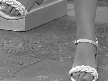 Close-up of a foot wearing a sandal with a woven design on a concrete surface.