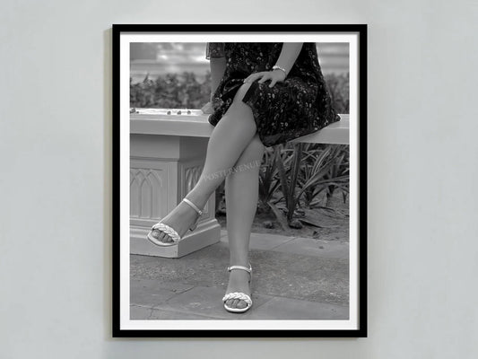 Framed black and white photograph of a person sitting outdoors wearing high heels.