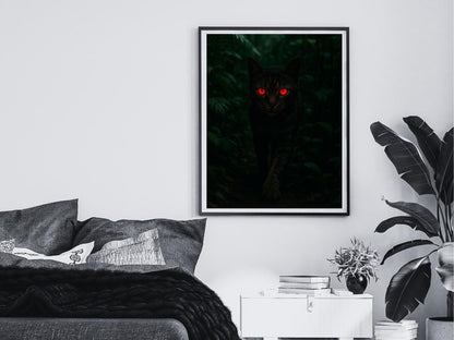 Framed artwork of a cat with red eyes on a wall above a bed.